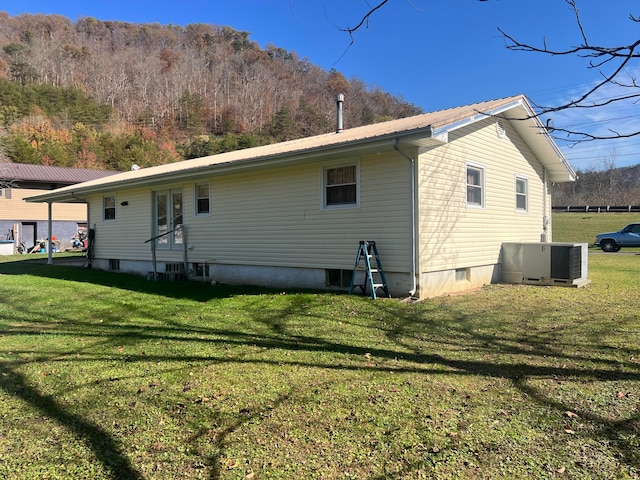 back of house with central air condition unit and a lawn