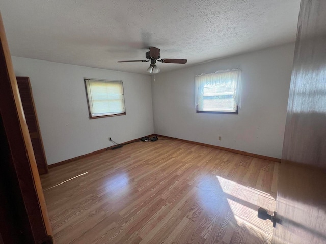 spare room with a textured ceiling, ceiling fan, and light hardwood / wood-style flooring