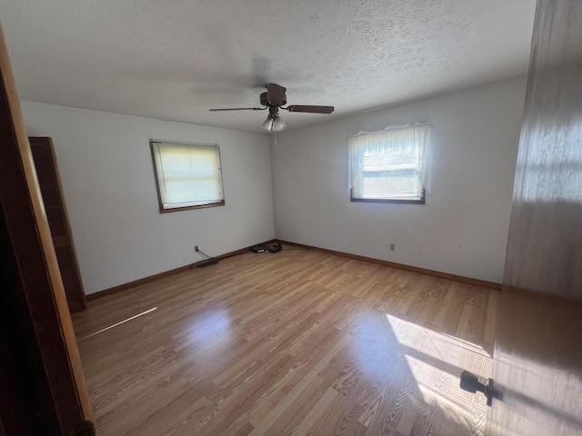 unfurnished room featuring wood finished floors, a textured ceiling, a ceiling fan, and baseboards