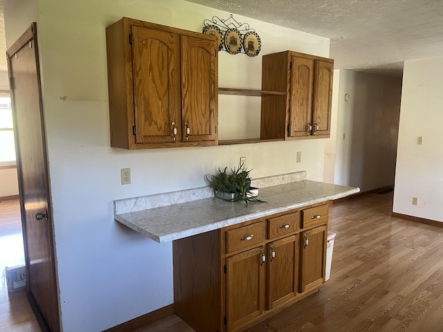 kitchen featuring a textured ceiling, brown cabinets, dark wood-style floors, and baseboards