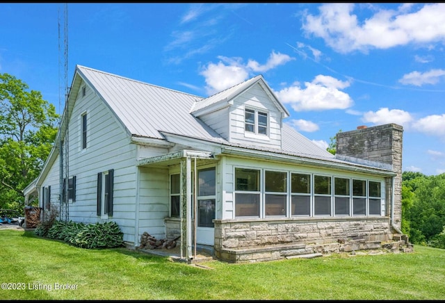 view of side of home with a sunroom and a lawn