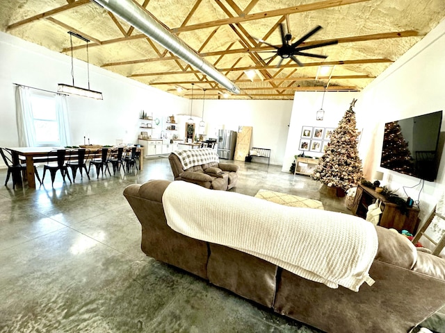 living area featuring a ceiling fan, finished concrete flooring, and a high ceiling