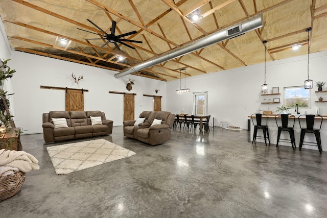 living area with a barn door, a high ceiling, finished concrete floors, and a ceiling fan