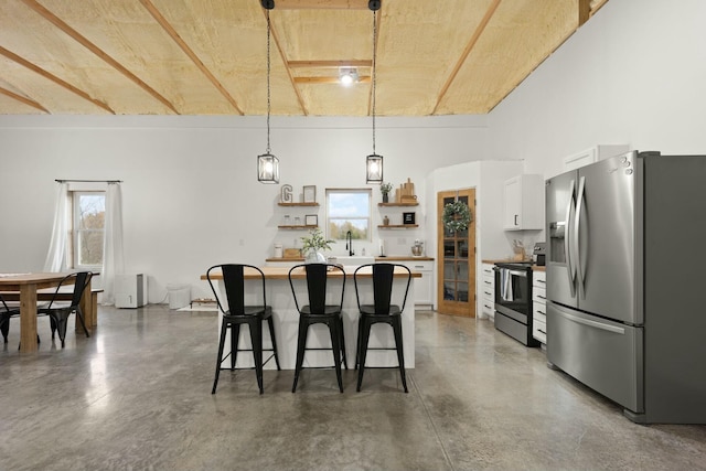 kitchen featuring finished concrete flooring, a breakfast bar, stainless steel appliances, white cabinetry, and open shelves