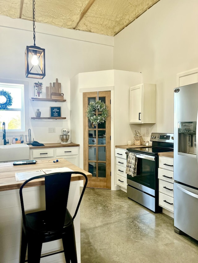 kitchen with white cabinets, hanging light fixtures, stainless steel appliances, concrete floors, and a sink