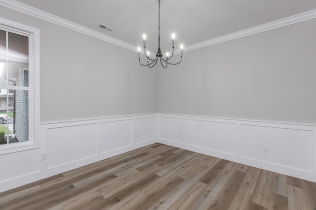 spare room featuring crown molding, an inviting chandelier, and light wood-type flooring