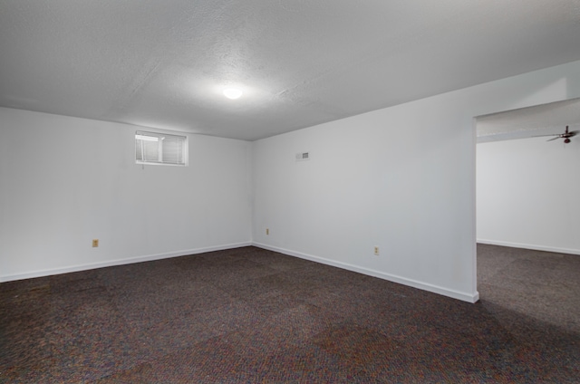 basement featuring a textured ceiling and dark colored carpet