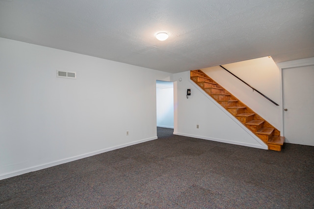 interior space featuring dark colored carpet and a textured ceiling