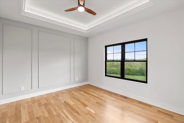 unfurnished room featuring a ceiling fan, light wood-type flooring, visible vents, baseboards, and a raised ceiling