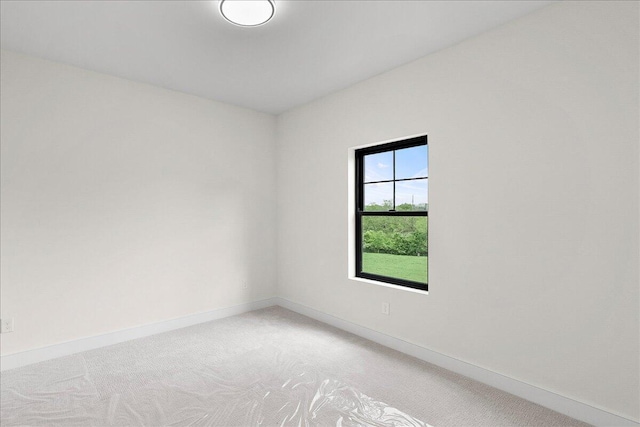 empty room featuring light carpet and baseboards