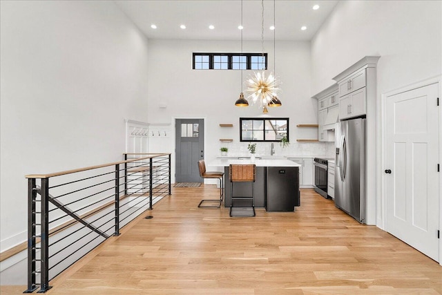 kitchen featuring a center island, open shelves, light countertops, appliances with stainless steel finishes, and a high ceiling