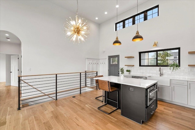 kitchen featuring light countertops, open shelves, a high ceiling, and a kitchen island