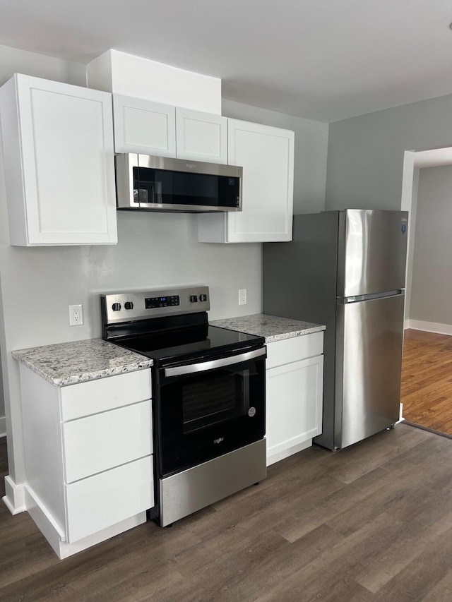 kitchen with light stone countertops, white cabinetry, dark wood-type flooring, and appliances with stainless steel finishes