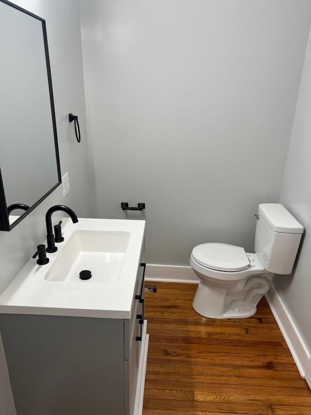 bathroom featuring wood-type flooring, vanity, and toilet