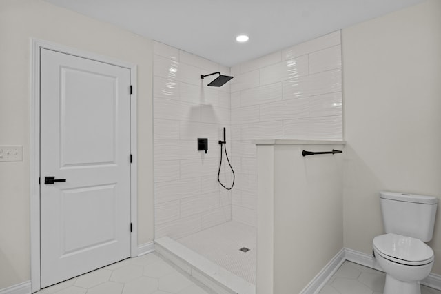 bathroom with tile patterned flooring, a tile shower, and toilet