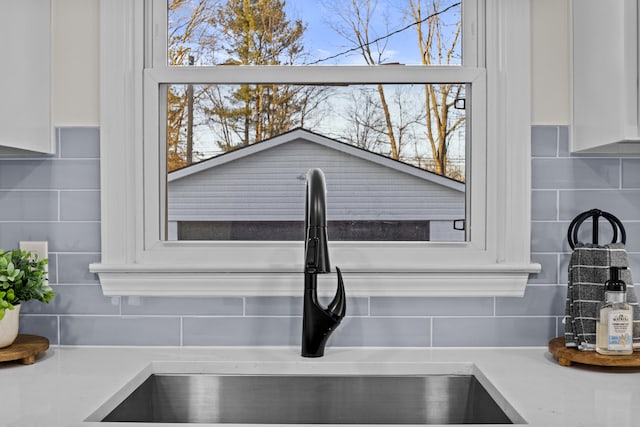 details featuring tasteful backsplash, sink, and white cabinets