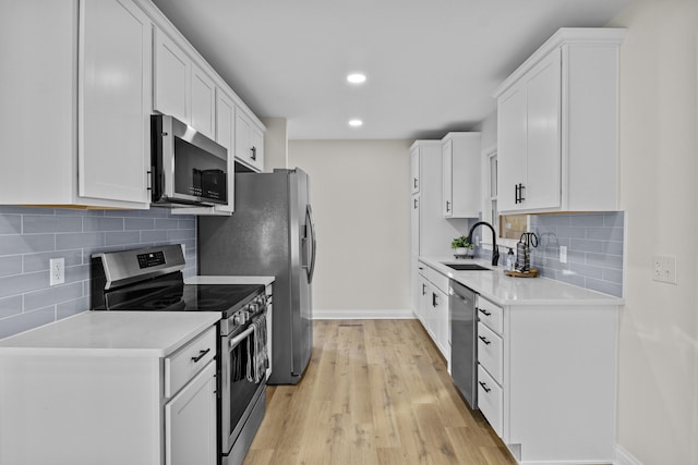 kitchen featuring sink, white cabinetry, backsplash, stainless steel appliances, and light wood-type flooring