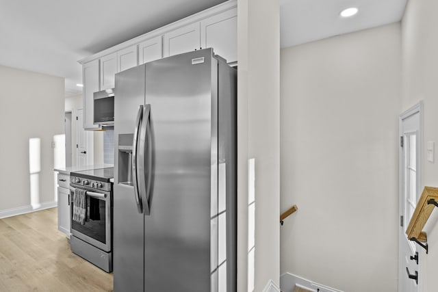 kitchen with white cabinetry, appliances with stainless steel finishes, and light hardwood / wood-style floors