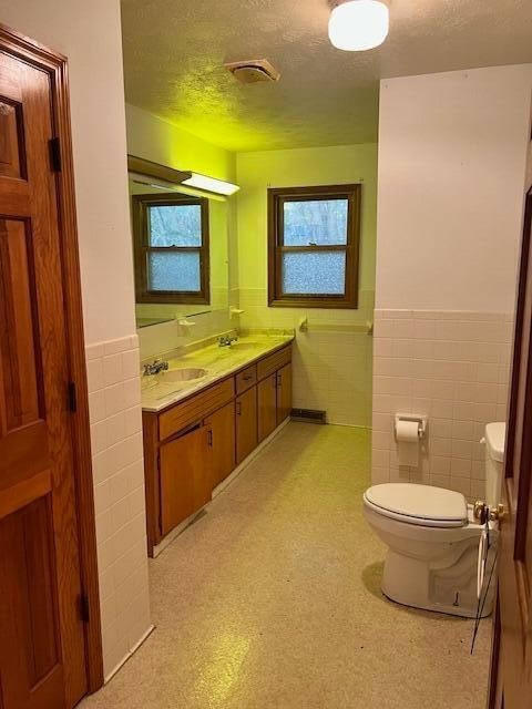 bathroom with vanity, tile walls, and toilet