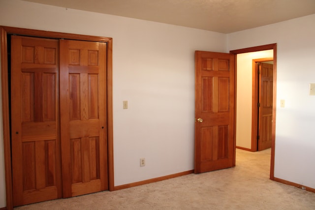 unfurnished bedroom featuring light carpet and a closet