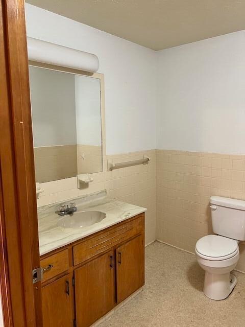 bathroom featuring vanity, tile walls, and toilet