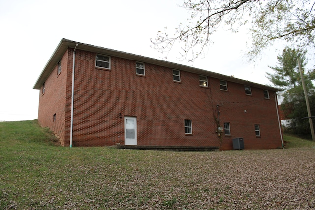 back of property featuring central air condition unit and a yard