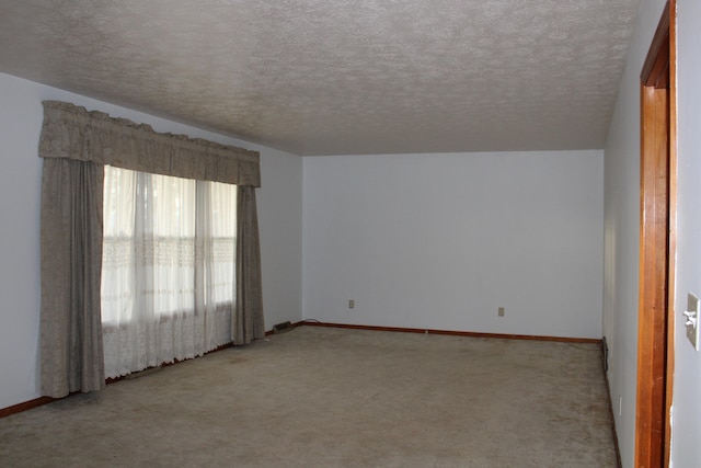 spare room featuring a textured ceiling, light colored carpet, and vaulted ceiling