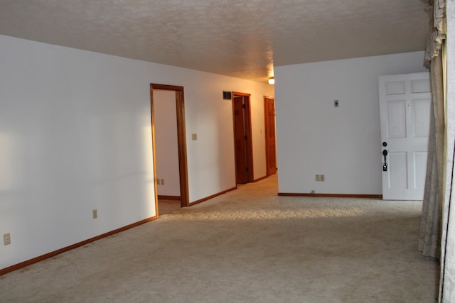 spare room with light carpet and a textured ceiling