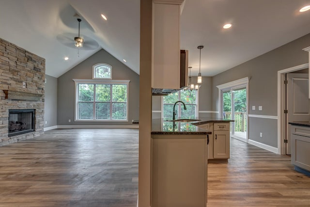 kitchen featuring dark stone counters, hardwood / wood-style floors, hanging light fixtures, and sink