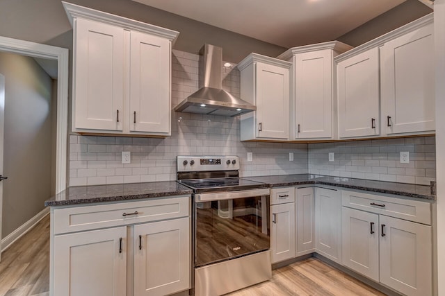 kitchen with white cabinetry, wall chimney range hood, stainless steel range with electric cooktop, and backsplash