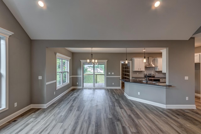 kitchen featuring white cabinetry, tasteful backsplash, wall chimney exhaust hood, hardwood / wood-style floors, and pendant lighting