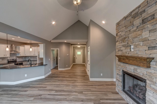 kitchen featuring electric stove, hanging light fixtures, light hardwood / wood-style floors, white cabinets, and wall chimney exhaust hood