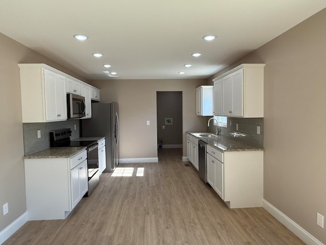 kitchen featuring appliances with stainless steel finishes, light wood-type flooring, white cabinetry, and sink