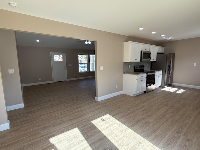 kitchen featuring stainless steel appliances, white cabinetry, hardwood / wood-style flooring, and light stone counters