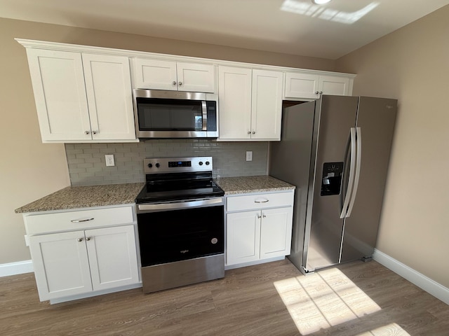 kitchen with white cabinets, light hardwood / wood-style floors, and appliances with stainless steel finishes