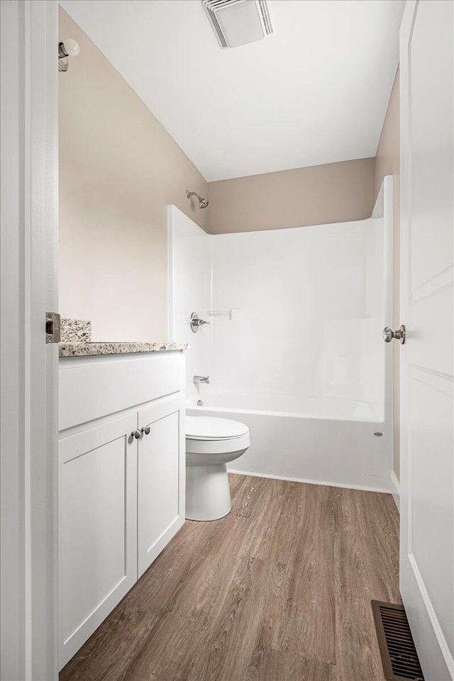 full bathroom with hardwood / wood-style flooring, vanity, shower / bathtub combination, and toilet