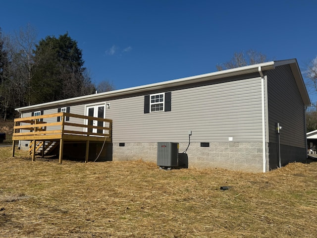 rear view of house featuring cooling unit, a lawn, and a wooden deck