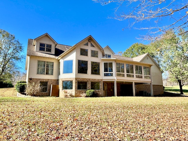 rear view of property featuring a sunroom and a yard