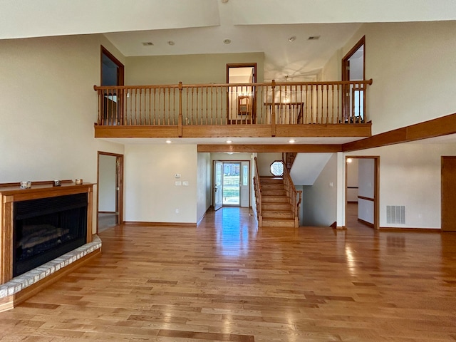 unfurnished living room featuring a towering ceiling and hardwood / wood-style flooring