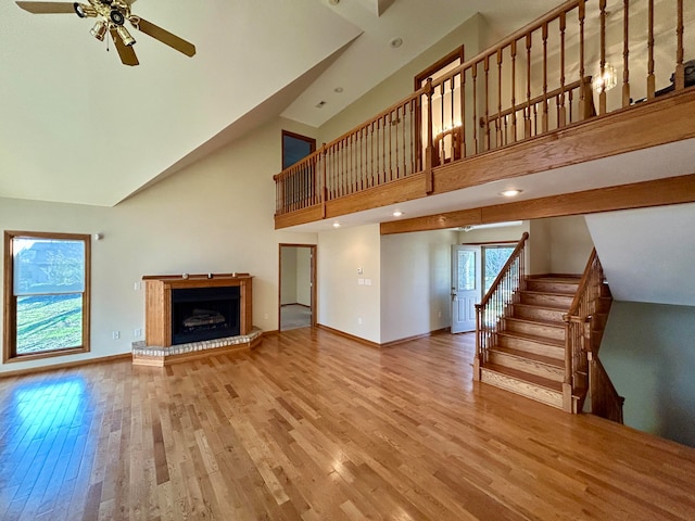 unfurnished living room featuring ceiling fan, light wood-type flooring, and high vaulted ceiling