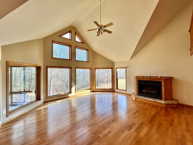 unfurnished living room with ceiling fan, plenty of natural light, high vaulted ceiling, and light hardwood / wood-style flooring