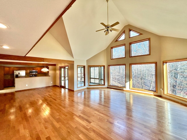 unfurnished living room featuring a healthy amount of sunlight, light hardwood / wood-style floors, and high vaulted ceiling