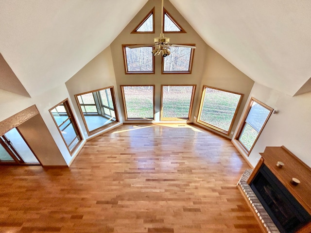 unfurnished living room featuring a wealth of natural light, ceiling fan, vaulted ceiling, and light wood-type flooring