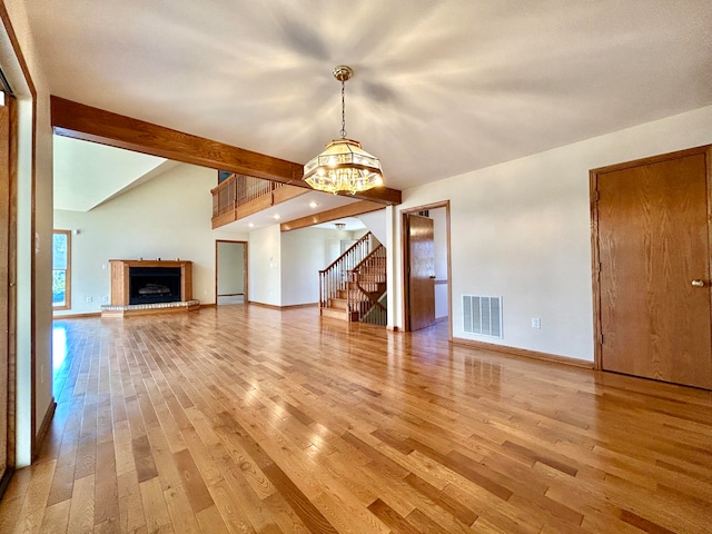 unfurnished living room featuring vaulted ceiling with beams, an inviting chandelier, and hardwood / wood-style flooring