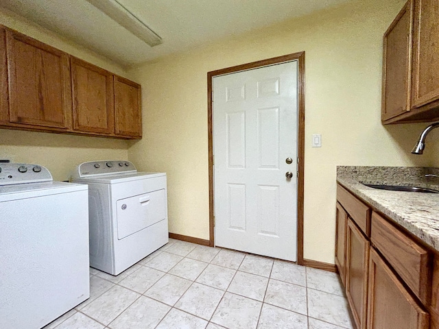 laundry area with light tile patterned flooring, cabinets, separate washer and dryer, and sink