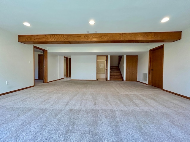 empty room featuring beamed ceiling and light colored carpet