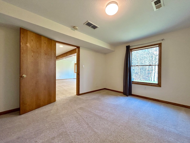 spare room featuring light colored carpet and a textured ceiling