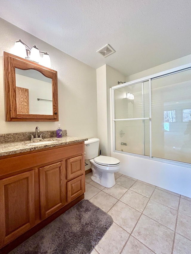 full bathroom featuring vanity, bath / shower combo with glass door, tile patterned flooring, toilet, and a textured ceiling