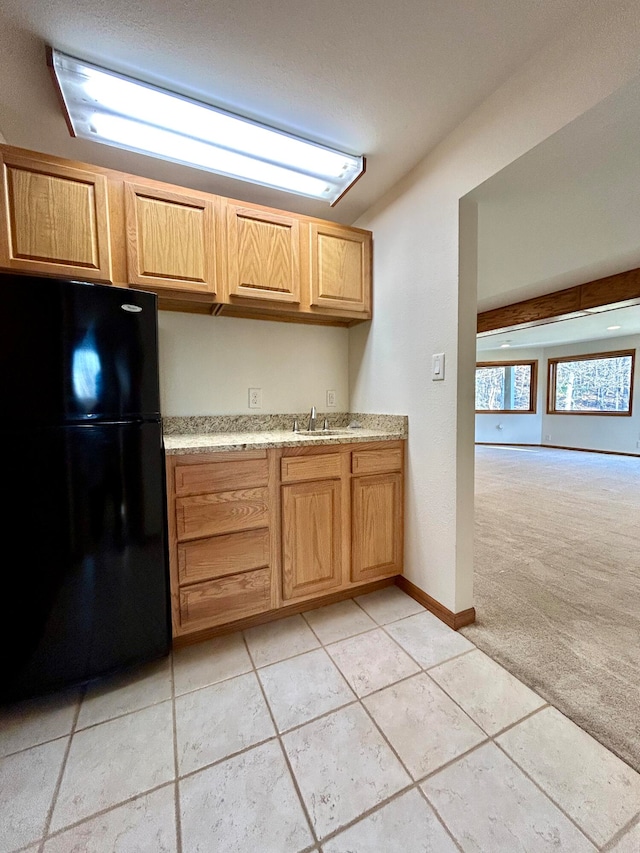 kitchen with light carpet, black refrigerator, and sink