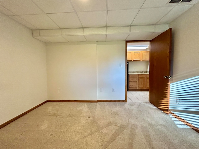 unfurnished room featuring a paneled ceiling and light colored carpet